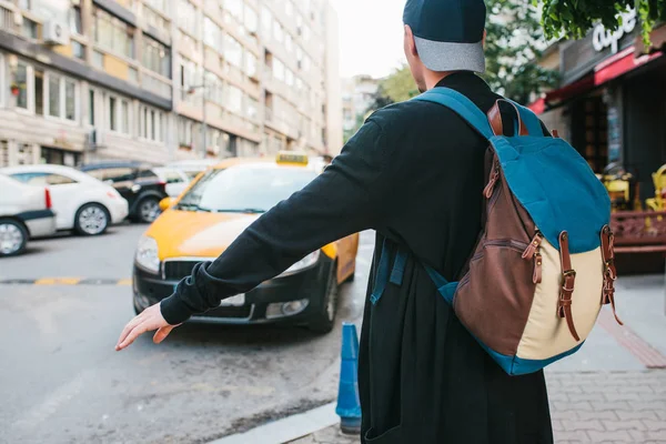 Jeune touriste masculin avec un sac à dos dans la grande ville attend un taxi. Voyage. Visites guidées. Voyages . — Photo