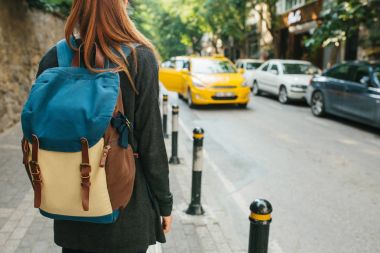 Genç turist kız büyük şehirde bir sırt çantası ile bir taksi bekliyor. Yolculuk. Gezi. Seyahat.