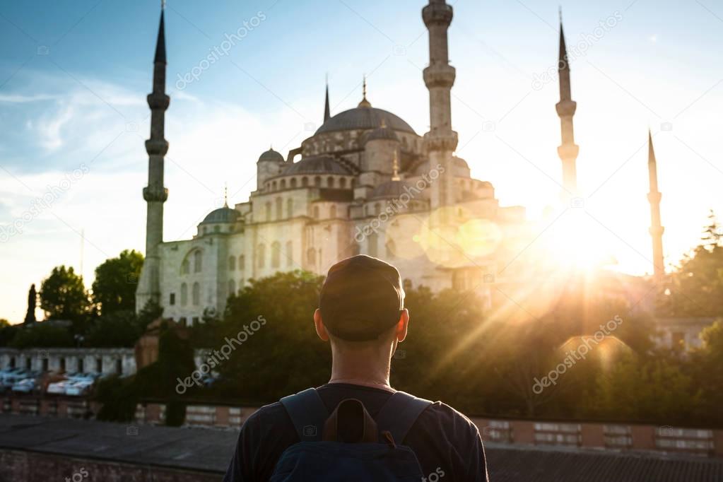 A man in a baseball cap with a backpack next to the blue mosque is a famous sight in Istanbul. Travel, tourism, sightseeing.