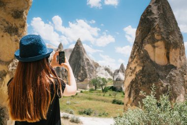 Bir turist kız telefonda hills Kapadokya Türkiye'de güzel bir manzarasına anısına bir fotoğraf yapar. Seyahat, turizm, hiking tatil.