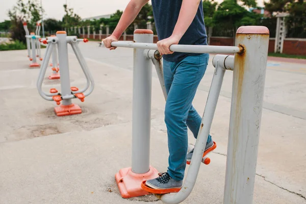 Un homme s'entraîne sur des équipements sportifs dans une ville en plein air. Le concept d'un mode de vie sain et l'accessibilité de l'entraînement sportif pour chaque personne. Équipements sportifs disponibles dans un lieu public . — Photo