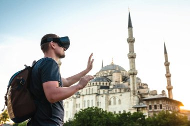 Sanal gerçeklik gözlüklü bir gezgin. Dünyanın dört bir yanından sanal seyahat kavramı. Arka plan, Türkiye'de Istanbul'da Sultanahmet Camii. Geleceğin teknolojisi kavramı.