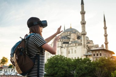 Sanal gerçeklik gözlüklü bir gezgin. Dünyanın dört bir yanından sanal seyahat kavramı. Arka plan, Türkiye'de Istanbul'da Sultanahmet Camii. Geleceğin teknolojisi kavramı.