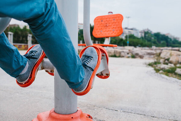 A man trains on sporting equipment in a city in the open air. The concept of a healthy lifestyle and accessibility of sports training for every person. Available sports equipment in a public place.