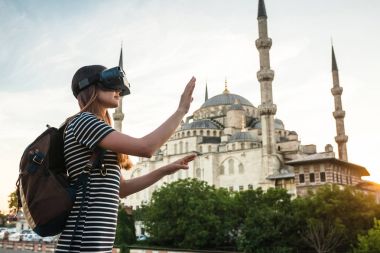 Sanal gerçeklik gözlüklü bir gezgin. Dünyanın dört bir yanından sanal seyahat kavramı. Arka plan, Türkiye'de Istanbul'da Sultanahmet Camii. Geleceğin teknolojisi kavramı.