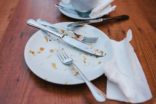 Dirty plate. Empty plate after eating place on wooden table in coffee shop. — Stock Photo, Image