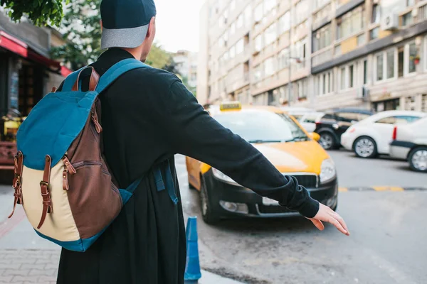 Giovane turista maschio con uno zaino nella grande città è in attesa di un taxi. Viaggio. Giro turistico. Viaggio . — Foto Stock