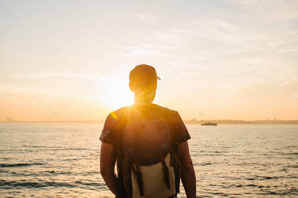 A tourist with a backpack on the coast. Travel, tourism, recreation. On the Sunset.