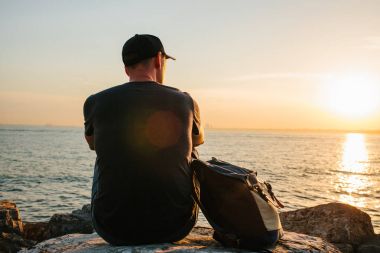 Deniz kenarı bir sırt çantası ile bir turist. Seyahat, turizm, rekreasyon. Sunset bulvarında.