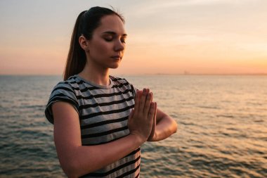Genç güzel kız pratik Yoga ve gün batımında denize yanında buzlu meditasyon. Spor. Yoga. Meditasyon. Rekreasyon. Tatil. Gevşeme.