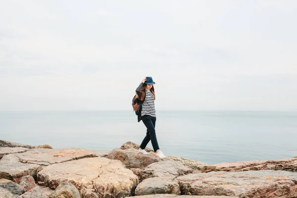 Ein Reisender mit Hut und Rucksack geht am Meer entlang. Reisen, Tourismus, Freiheit. — Stockfoto