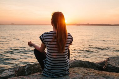 Genç güzel kız pratik Yoga ve gün batımında denize yanında buzlu meditasyon. Spor. Yoga. Meditasyon. Rekreasyon. Tatil. Gevşeme.