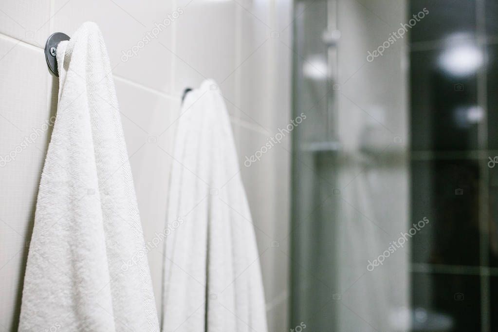 White towels hang on the wall in the bathroom. Cleanliness, shower.