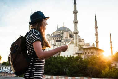 Bir sırt çantası ile şapkalı bir genç güzel Gezgin kız bir planın Sultanahmet Camii - Istanbul 'un ünlü görüş yanında izliyor. Seyahat, turizm, gezi.