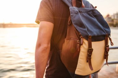 Erkek turist Istanbul'da Boğaz'ın yanındaki günbatımında bir sırt çantası ile. Hiking, tatil eğlence kavramı.