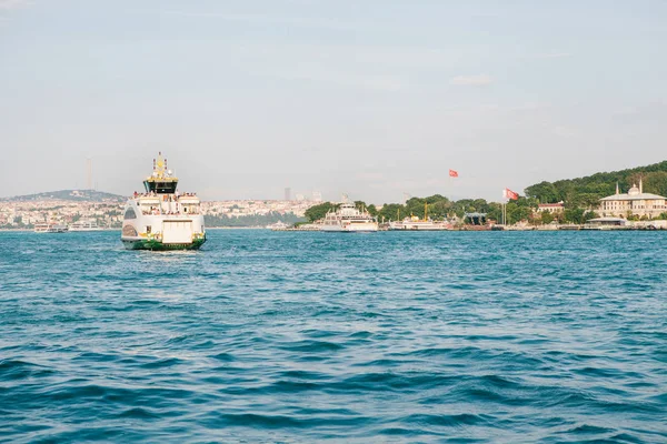 El barco navega a lo largo del agua azul del Bósforo con el telón de fondo de una hermosa vista de la parte europea de Estambul. Vistas panorámicas panorámicas. Viajar, descansar, vacaciones . — Foto de Stock