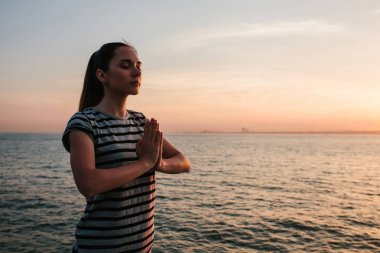 Genç güzel kız pratik Yoga ve gün batımında denize yanında buzlu meditasyon. Spor. Yoga. Meditasyon. Rekreasyon. Tatil. Gevşeme.