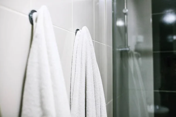 Fehér törölközőt kapaszkodni a fal, a fürdőszobában. Tisztaság, zuhanyzó. — Stock Fotó