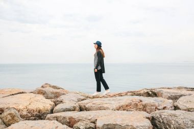 Şapkalı bir gezgin deniz kenarında yürüyor. Seyahat, turizm, özgürlük.