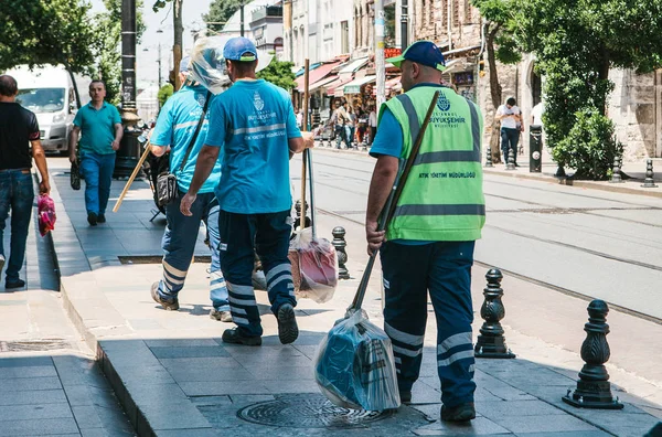 Istanbul, 15 Haziran 2017: Üç kapıcı üniformalı süpürge ve toz tava tutan caddeden aşağı yürüyüş sokak.