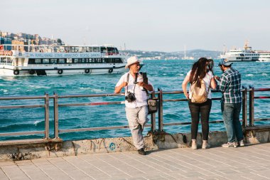 Istanbul, 15 Haziran 2017: Yaşlı fotoğrafçı ve iskeleye iki genç insan. Türkiye. Boğaz'ın arka planda olduğunu.