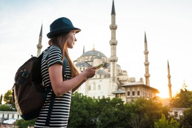 Bir sırt çantası ile şapkalı bir genç güzel Gezgin kız bir planın Sultanahmet Camii - Istanbul 'un ünlü görüş yanında izliyor. Seyahat, turizm, gezi.