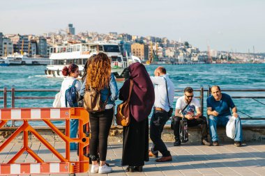 Istanbul, 15 Haziran 2017: Bir grup insan Galata Köprüsü yakınlarındaki Eminony alanda boğaz yakınındaki bekliyoruz. Cityscape ve feribot tekne ile arka plan manzara panorama.