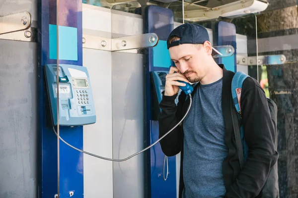 Ankesörlü telefon üzerinde konuşan genç çekici modern adam