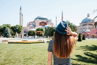 Istanbul, Türkiye'de ünlü Aya Sofya Camii yanındaki Sultanahmet Meydanı'nda arkadan şapkalı bir genç kız gezgin. Seyahat, turizm, gezi.