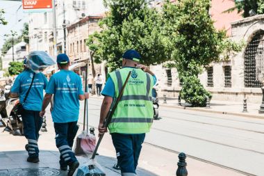 Istanbul, 15 Haziran 2017: Üç kapıcı üniformalı süpürge ve toz tava tutan caddeden aşağı yürüyüş sokak.