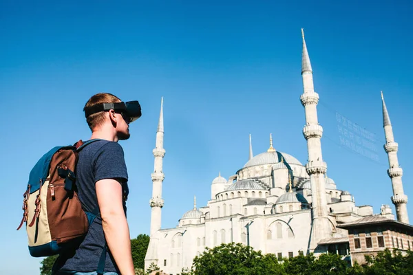 Sanal gerçeklik gözlüklü bir gezgin. Dünyanın dört bir yanından sanal seyahat kavramı. Arka planda Türkiye'de Istanbul'da Sultanahmet Camii. Geleceğin teknolojisi kavramı.