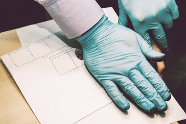 Araştırmacı suç şüphelisi üzerinden parmak izini alıyor. Soruşturma bir suçtur. Suç.