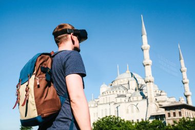 Sanal gerçeklik gözlüklü bir gezgin. Dünyanın dört bir yanından sanal seyahat kavramı. Arka planda Türkiye'de Istanbul'da Sultanahmet Camii. Geleceğin teknolojisi kavramı.