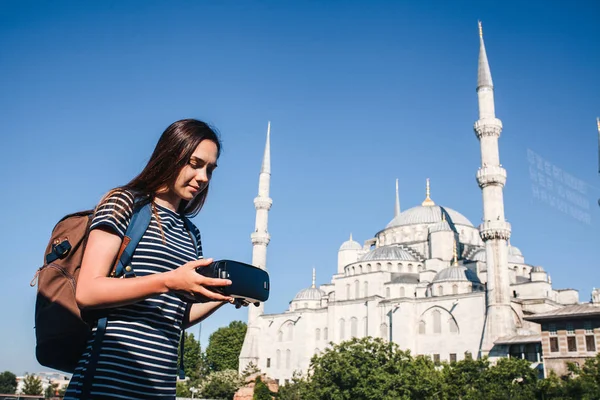 Sanal gerçeklik gözlüklü bir gezgin. Dünyanın dört bir yanından sanal seyahat kavramı. Arka planda Türkiye'de Istanbul'da Sultanahmet Camii. Geleceğin teknolojisi kavramı.