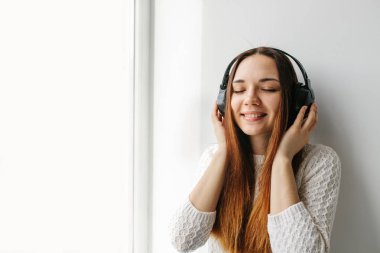Güzel kız pencerenin yanındaki müzik dinlerken