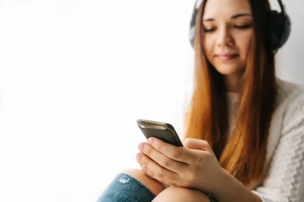 Menina bonita está ouvindo a música. Foco seletivo no gadget . — Fotografia de Stock