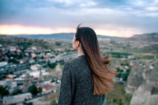 Young woman tourist from a high point looking at the sunset over the city of Goreme in Cappadocia in Turkey and dreaming. Tourism, vacations, rest.