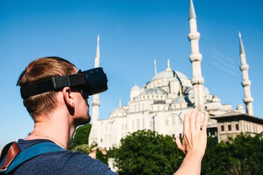 Sanal gerçeklik gözlüklü bir gezgin. Dünyanın dört bir yanından sanal seyahat kavramı. Arka planda Türkiye'de Istanbul'da Sultanahmet Camii. Geleceğin teknolojisi kavramı.
