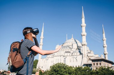 Sanal gerçeklik gözlüklü bir gezgin. Dünyanın dört bir yanından sanal seyahat kavramı. Arka planda Türkiye'de Istanbul'da Sultanahmet Camii. Geleceğin teknolojisi kavramı.