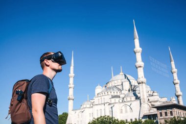Sanal gerçeklik gözlüklü bir gezgin. Dünyanın dört bir yanından sanal seyahat kavramı. Arka planda Türkiye'de Istanbul'da Sultanahmet Camii. Geleceğin teknolojisi kavramı.
