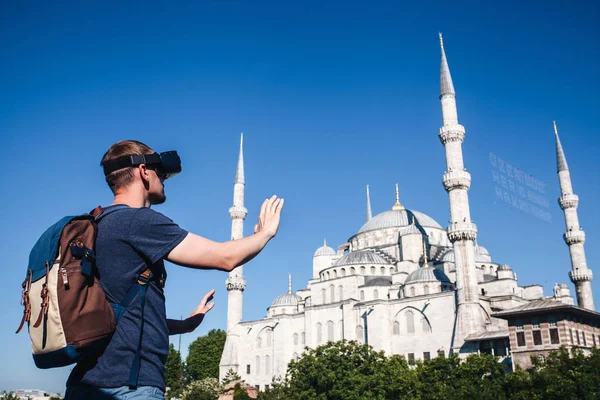 Sanal gerçeklik gözlüklü bir gezgin. Dünyanın dört bir yanından sanal seyahat kavramı. Arka planda Türkiye'de Istanbul'da Sultanahmet Camii. Geleceğin teknolojisi kavramı.