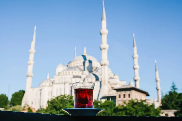 Té negro turco aromático tradicional en un vaso en forma de tulipán. En el fondo, la Mezquita Azul también se llama Sultanahmet en Estambul, Turquía . —  Fotos de Stock
