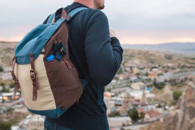 Bir turist bir yükseklikten günbatımında bir dağ town üzerinde görünüyor. Turizm, hiking kavramı. Backpacker