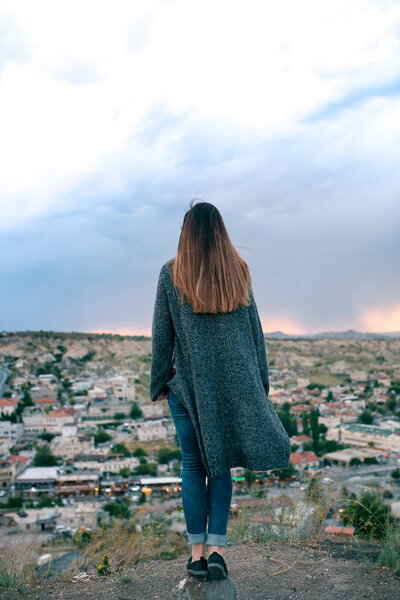Young woman tourist from a high point looking at the sunset over the city of Goreme in Cappadocia in Turkey and dreaming. Tourism, vacations, rest.