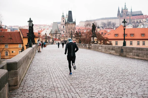 Praga, 24 grudnia 2016 roku: Lekkoatletka mężczyzna ma poranne bieganie w zimie na Most Karola w Pradze, w Republice Czeskiej. Zdrowy styl życia. Zajęcia sportowe — Zdjęcie stockowe