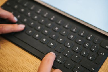 Tablet klavye Alman harflerle ellerinde. Uzaktan çalışma, freelancing, bloglama, tasarım ve iş üstünde bilgisayar ile ilgili diğer meslekler kavramı.