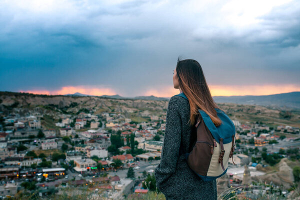 Young woman tourist from a high point looking at the sunset over the city of Goreme in Turkey and dreaming. Cappadocia. Tourism, rest, vacation.
