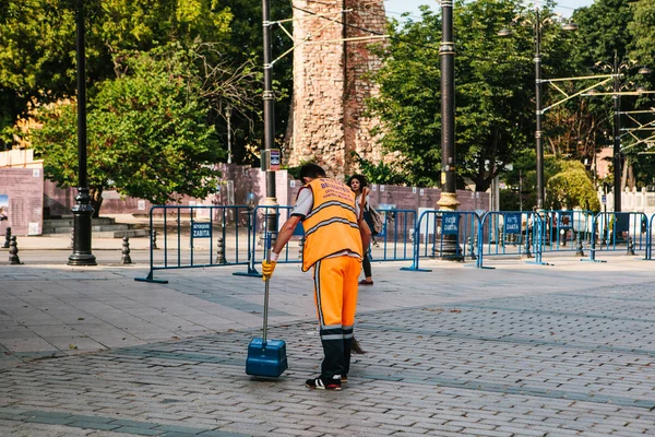 Istanbul, 15 Haziran 2017: kapıcı parlak turuncu üniformalı Sultanahmet semtinde sokakta döşemeyi süpürme.