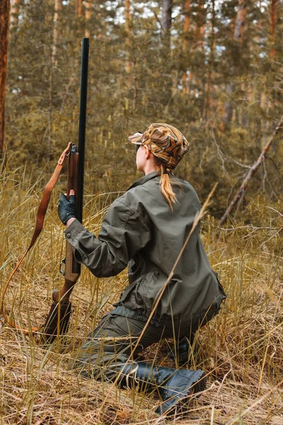 Woman hunter in the woods. Autumn hunting season. Outdoor sports.