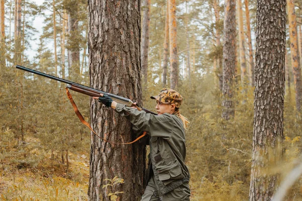 Woman hunter in the woods. Autumn hunting season. Outdoor sports.